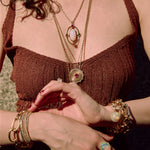 Person wearing gold necklaces and bracelets with a ring on hands.