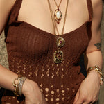 Person wearing a brown top with necklaces and bracelets.