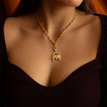 Gold necklace with a horse pendant on a person's neck.