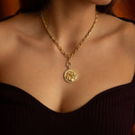 Gold necklace with a pendant on a person's neck.