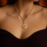 Gold necklace with a pendant on a person's neck.