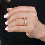 Hand wearing a gold ring with diamonds on a black background