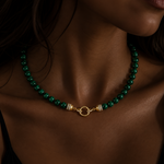 A close-up of a woman wearing a beaded necklace with malachite bead chain

