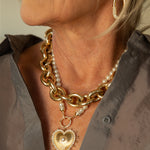 The Cassandane Mega Heart Medallion stuns with radiant gold rays, diamond accents, and signature beaded details — worn bold on a pearl necklace and layered with a chunky Italian made chain.
