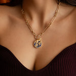 A bold lapis forest medallion with pavé diamond accents, paired with a golden horse charm and worn on a statement trombone chain