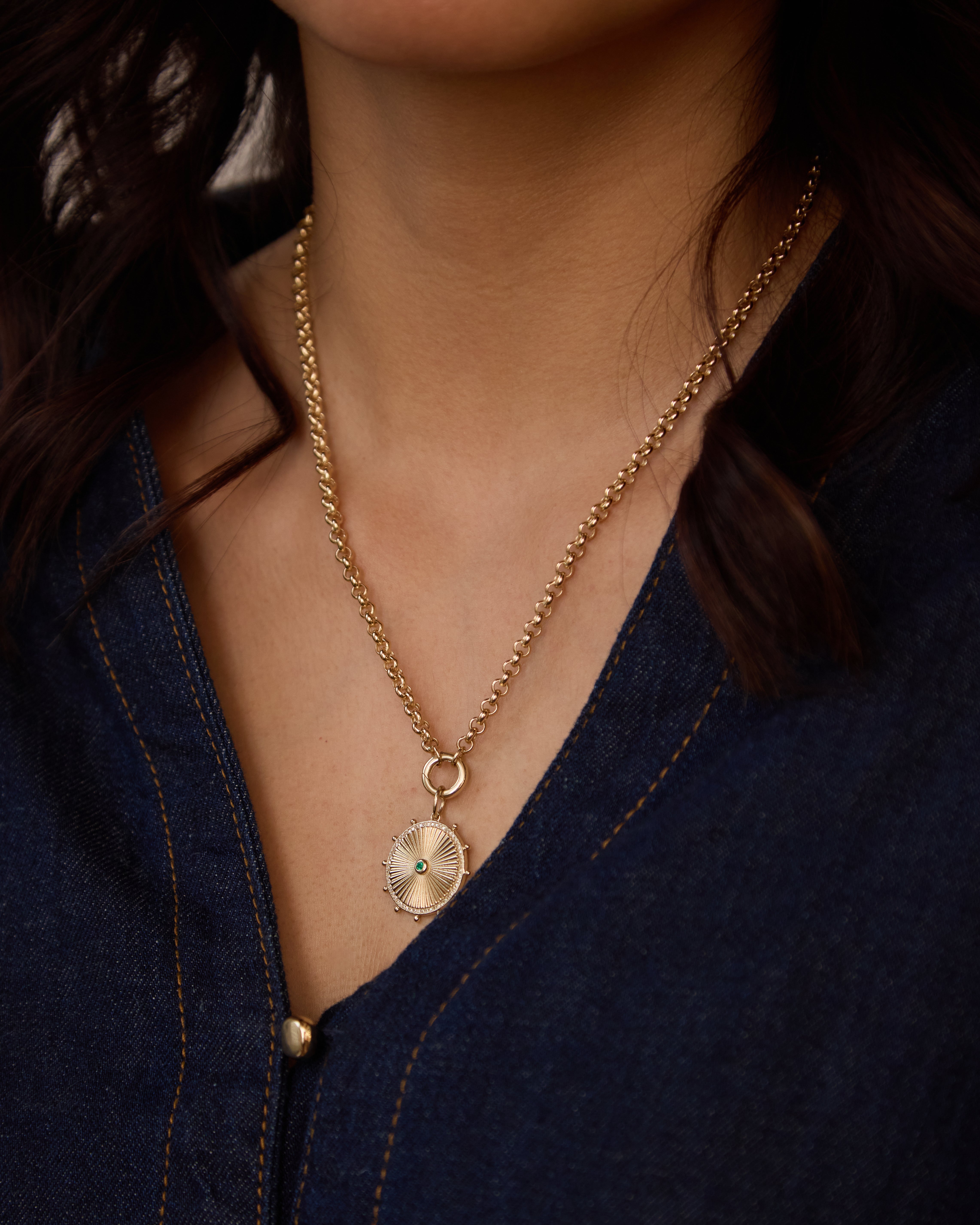 Our radiant sun medallion shines with diamond rays and a vibrant emerald center, strung on a classic gold rolo chain.