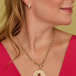 Close-up of a woman wearing the Lionheart Aurelia tourmaline charm in 14K gold with diamond bead border 