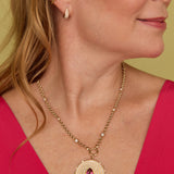 Close-up of a woman wearing the Lionheart Aurelia tourmaline charm in 14K gold with diamond bead border 