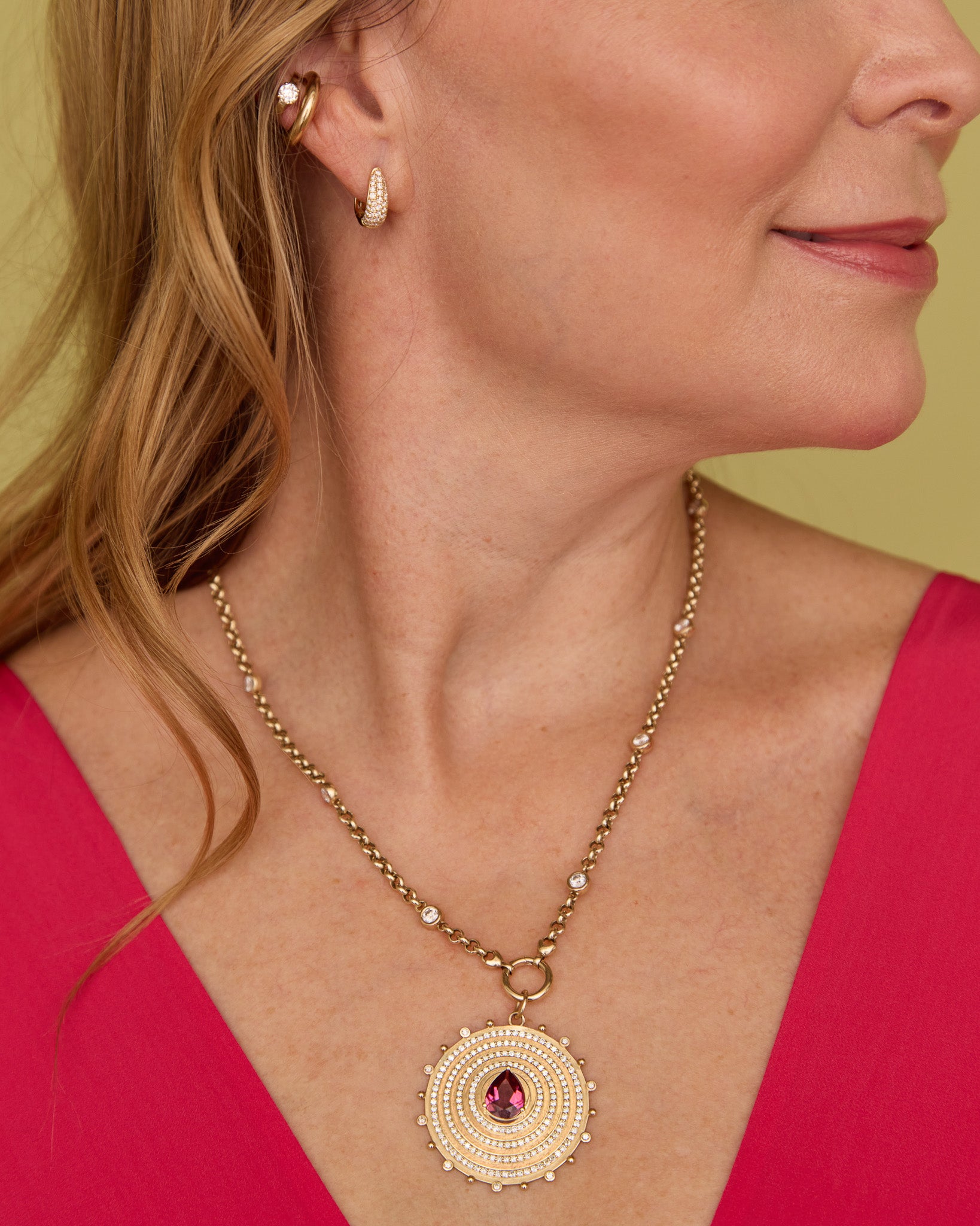 Close-up of a woman wearing the Lionheart Aurelia tourmaline charm in 14K gold with diamond bead border 